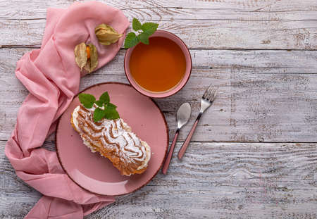 Custard cake with cream on a pink dish with a cup of green teaの写真素材