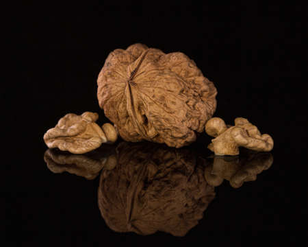 walnut and walnut kernels on a dark brown background with reflection