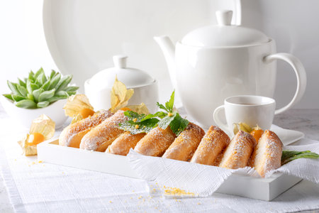 Delicious puff pastry rolls with powdered sugar and mint on white table