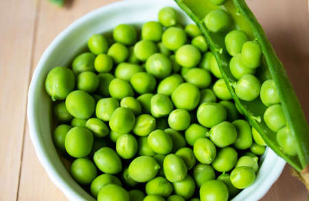 Green pea in bowl on a wooden backgroundの写真素材