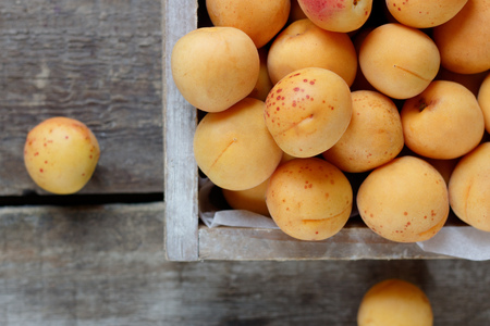 Ripe apricots in a wooden box on a wooden tableの写真素材
