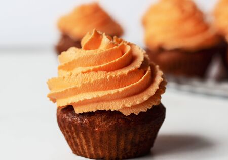 Fresh and tasty with orange frosting cupcakes on white backgroundの写真素材