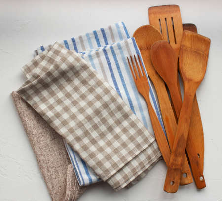 wooden kitchen utensils and kitchen napkins on white background top view