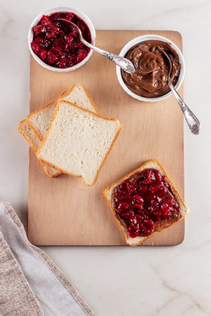 Sandwich with chocolate butter and cherry jam on wooden background. Breakfast with coffeeの写真素材