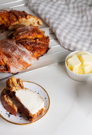 Braided bread with stuffed with cooked condensed milk and nuts. Slice smeared with butter.