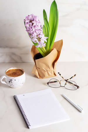 Spring Day. Cup of coffee, blank open diary mockup. Purple hyacinth in flower pot. Home office concept.の写真素材