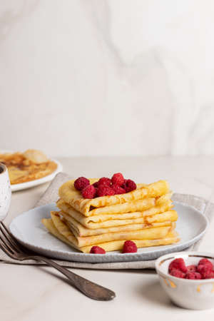 Stack golden pancakes or crepes with raspberries in a grey plate. Breakfast concept. Maslenitsa....