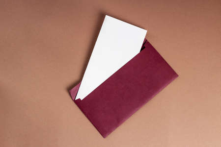 Postcard mockup horizontal, on a brown background, a red open envelope and a white sheetの写真素材