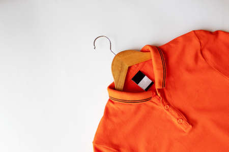 Orange blank t-shirt with blank clothing tag on hangers for clothesの写真素材