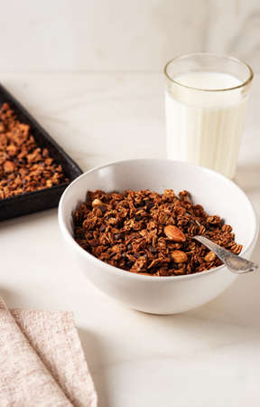 Homemade chocolate granola in a white plate with milk on a light background. Healthy breakfastの写真素材