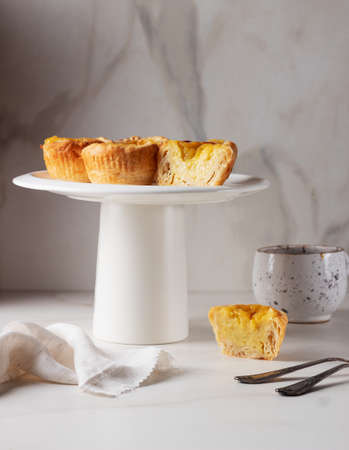 Pastel de Nata - portugese egg custard pies on white marble background.