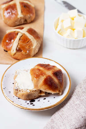 Fresh homemade Traditional Easter treats hot Cross Buns with raisins, served with butter and knife...
