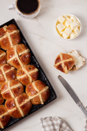 Fresh homemade Traditional Easter treats hot Cross Buns with raisins, served with butter and knife...