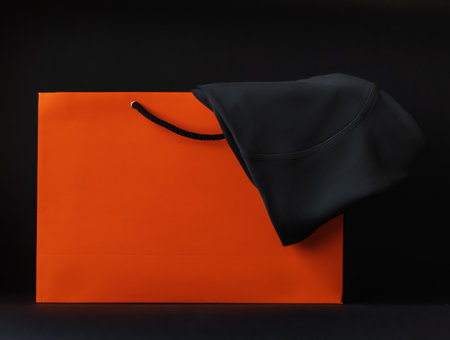 Bright orange paper bagand black pants is visible on a black background.の写真素材