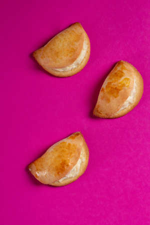 Sochniki, sochni, with cottage cheese. Cookies stuffed with cottage chees on a pink background. Copy...