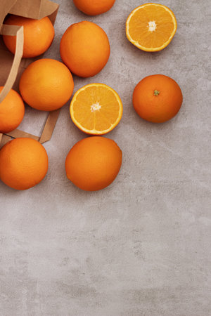 Fresh oranges in a brown paper bag on a gray background Sustainable packaging and zero waste conceptの写真素材