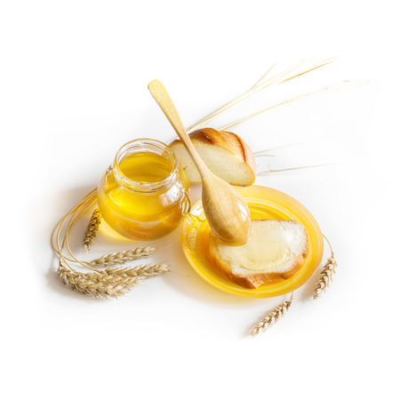white bread with honey and butter , honey in a jar with a spoon and ears of wheatの写真素材
