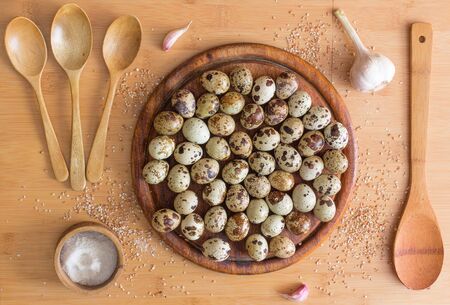 wooden spoons, salt, quail eggs, seeds crushed wheat, garlic, cutting Board on wooden background. Still life cooking quail eggs.の写真素材