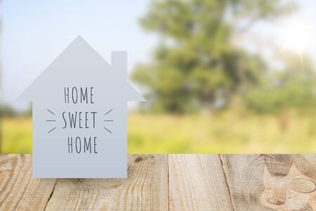 The house is made of paper with the inscription "home sweet home" in the blurry background scenery. Symbolizes the prospect of building a house.の写真素材