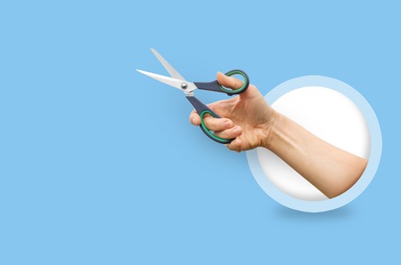 Scissors in the hands of women. Isolated on blue backgroundの写真素材