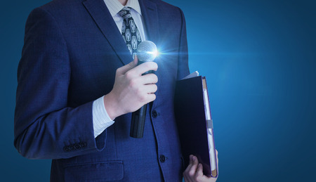 Businessman stands with a microphone.の写真素材