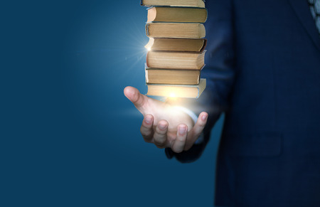 Businessman show stack of books on a blue background.の写真素材