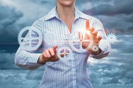 Businesswoman supports the gear mechanism. Symbolizes the control or manufacture.