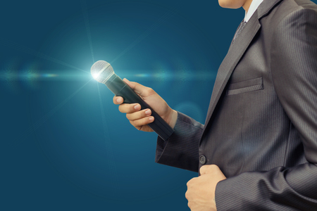 Businessman with a microphone on blurred background.の写真素材