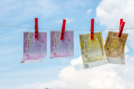 Euro banknotes weigh on the rope as linen against the sky.の写真素材
