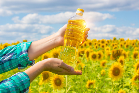 In the hands of the farmer sunflower oil on the background of sunflowers.の写真素材