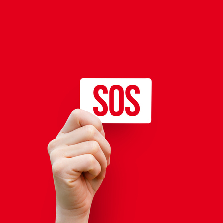 In the hand card with the inscription sos on a red background.の写真素材