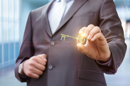 Businessman showing a key to success on blurred background.の写真素材