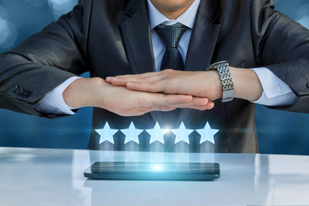 Business man protects a rating out of five stars.の写真素材