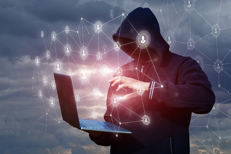 Hacker delves into the network through a laptop against the sky.の写真素材