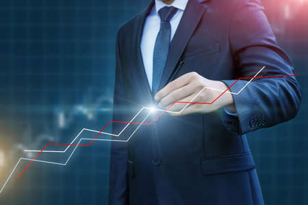 Businessman draws a graph of the dynamics of profit growth on blurred background.の写真素材