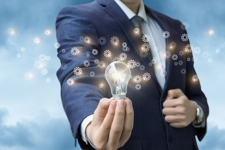 Light stays on in the hand of a businessman radiating gear. The concept of the idea as the business...