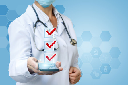 Doctor shows the list of performed treatment on a blue background.の写真素材