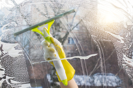 Hand cleaners with scraper cleans the foam in the window.の写真素材