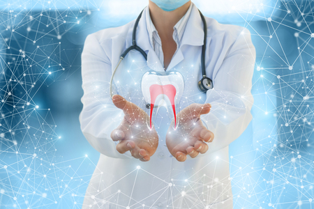 Doctor shows a tooth on a blue background.の写真素材