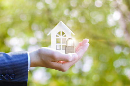 Hand agent with a house and castle. The concept of protection or insurance on the property.
