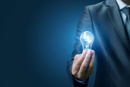 Businessman holding a light bulb with a glowing brain. The concept of the idea.