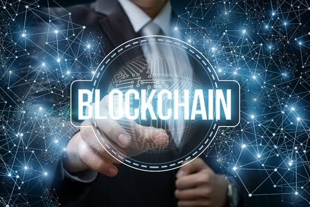 Businessman clicks on the block chain network on blue background. The concept of a new technology of...