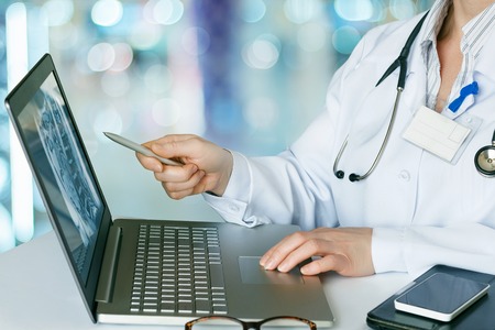 Doctor looks at the laptop at the table.