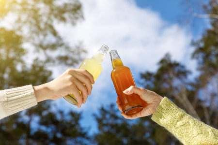 Clinking Beer bottles on a background of trees.の写真素材