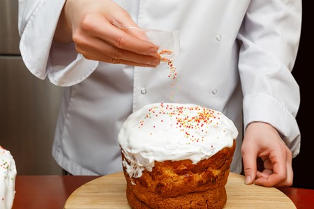 Chef decorates the cake sprinkled sweets balls.