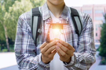 Student shows light bulb in the cap academic on blurred background .の写真素材