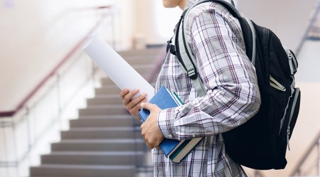 Student with backpack and books on the background of the ladder at the Institute.