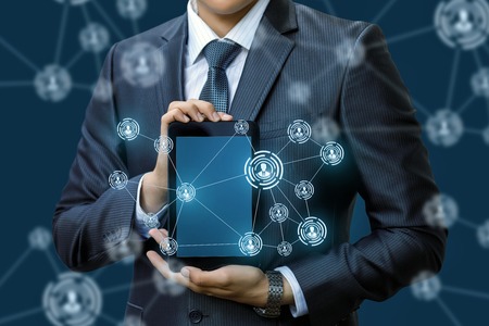 Businessman showing a network in the tablet on a blue background.の写真素材
