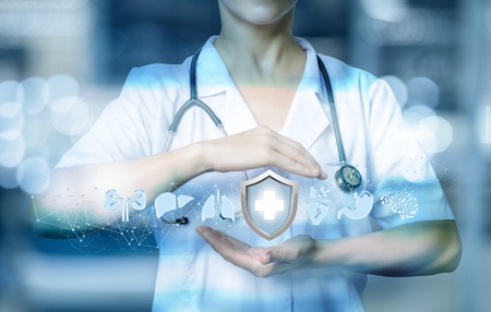 Health worker shows a gesture of protection of the internal organs on blurred background.の写真素材