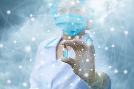 Health worker shows a tube with a cure against the sky.の写真素材